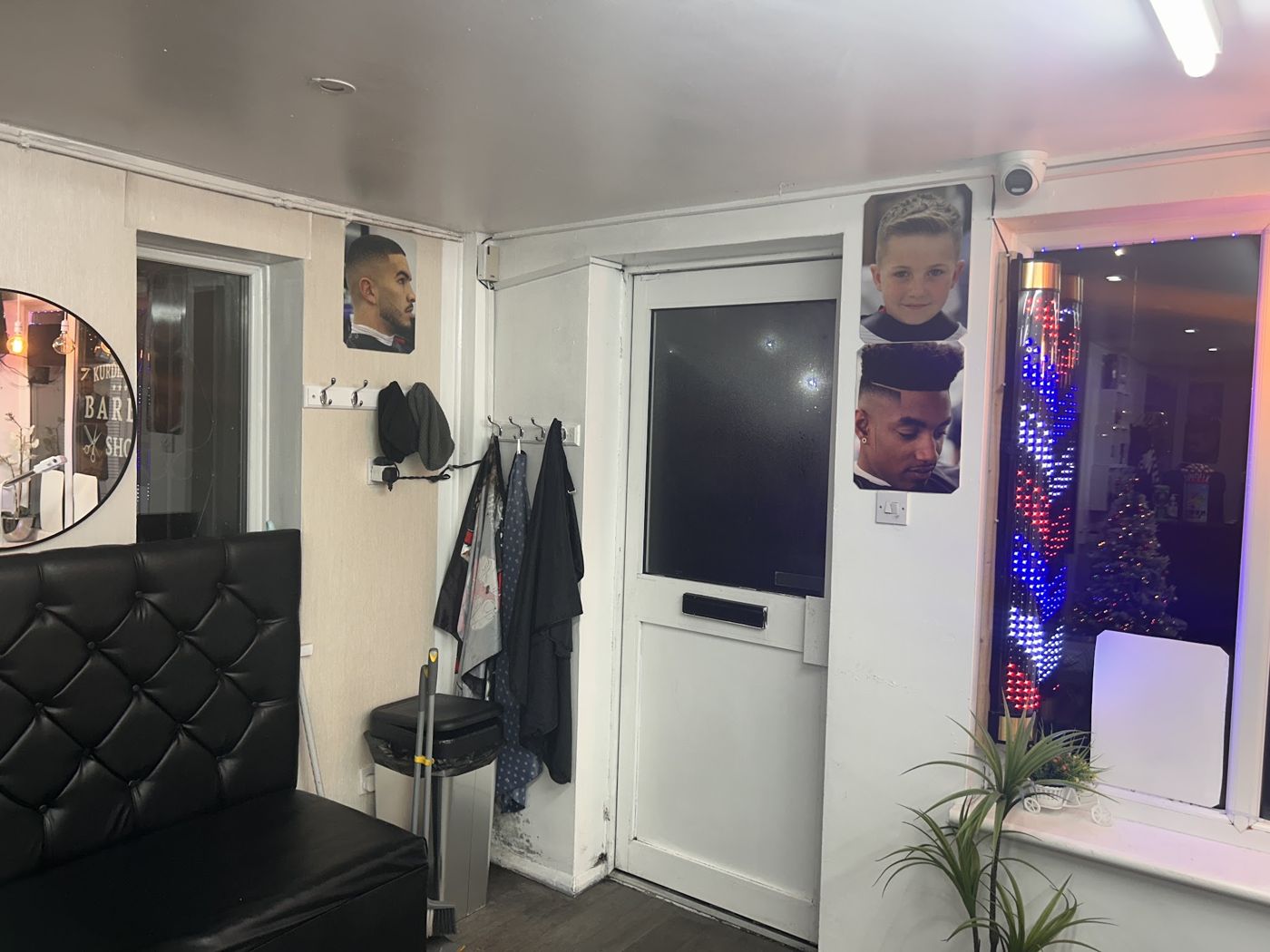 The entrance with a spinning barber pole and photos of haircuts on the door